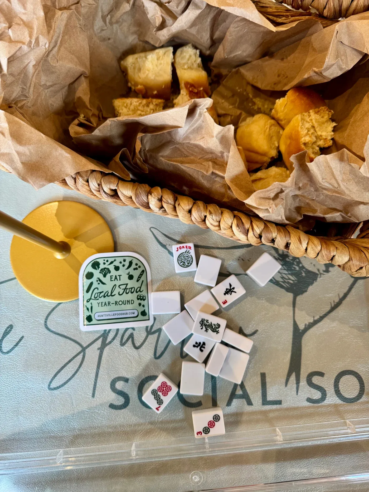 Mahjong tiles, a notebook, and tote bags arranged on a tabletop.
